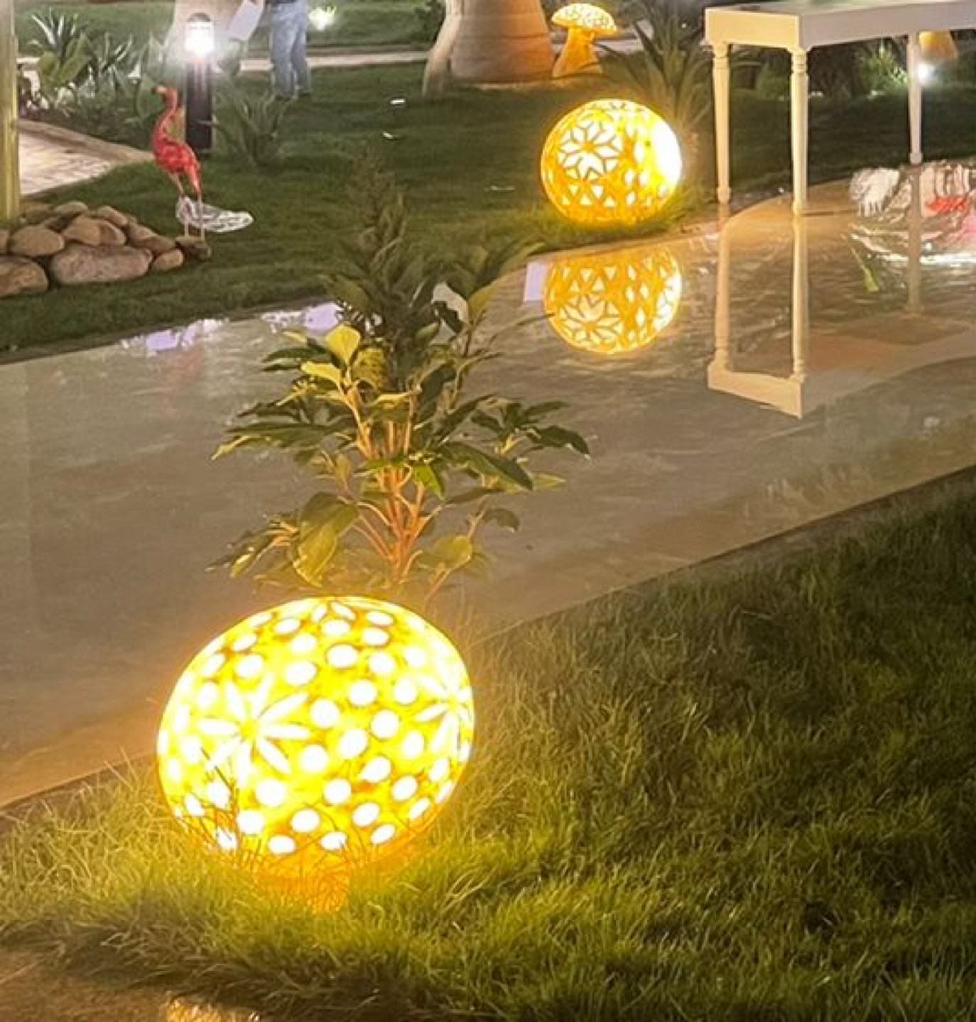 كرة إضاءة مزخرفة على العشب بجانب الممشى الرخامي